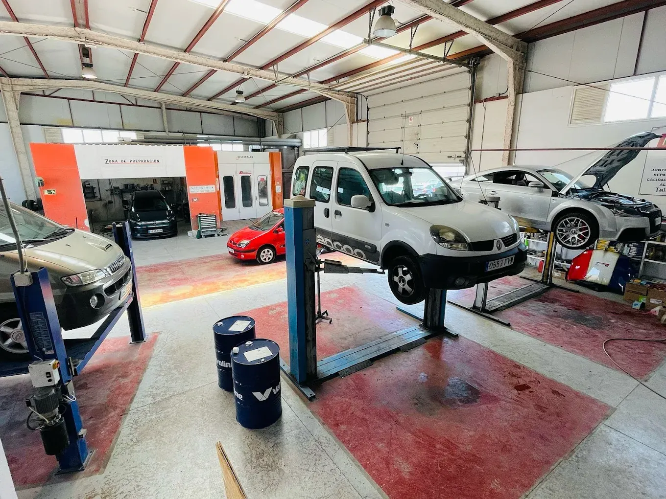 Interior del taller Pitbull Garage en Las Chafiras, con coches en los elevadores